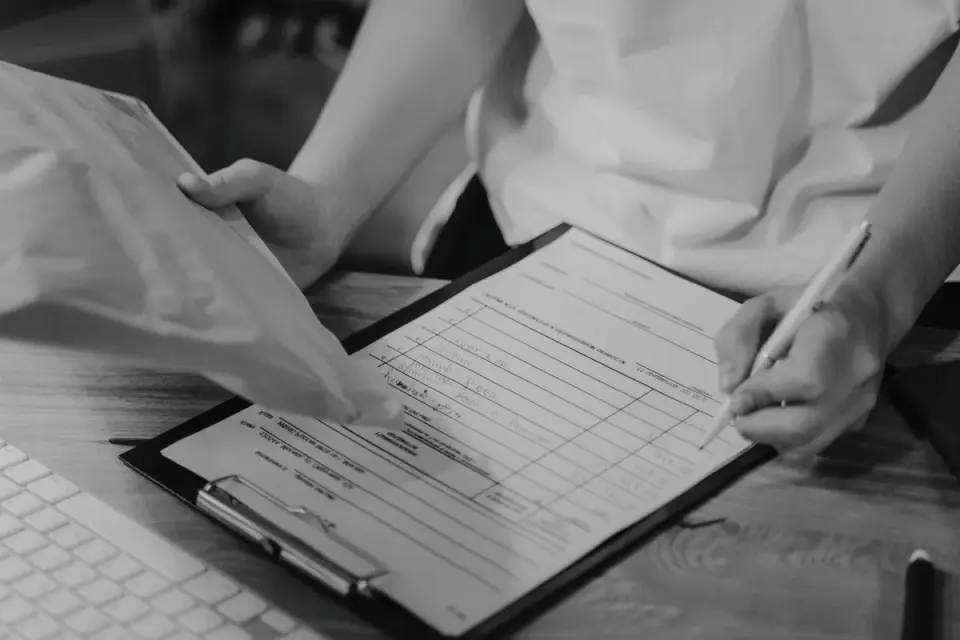 A boarding facility staff member reviewing a dog&#x27;s vaccination paperwork at check-in