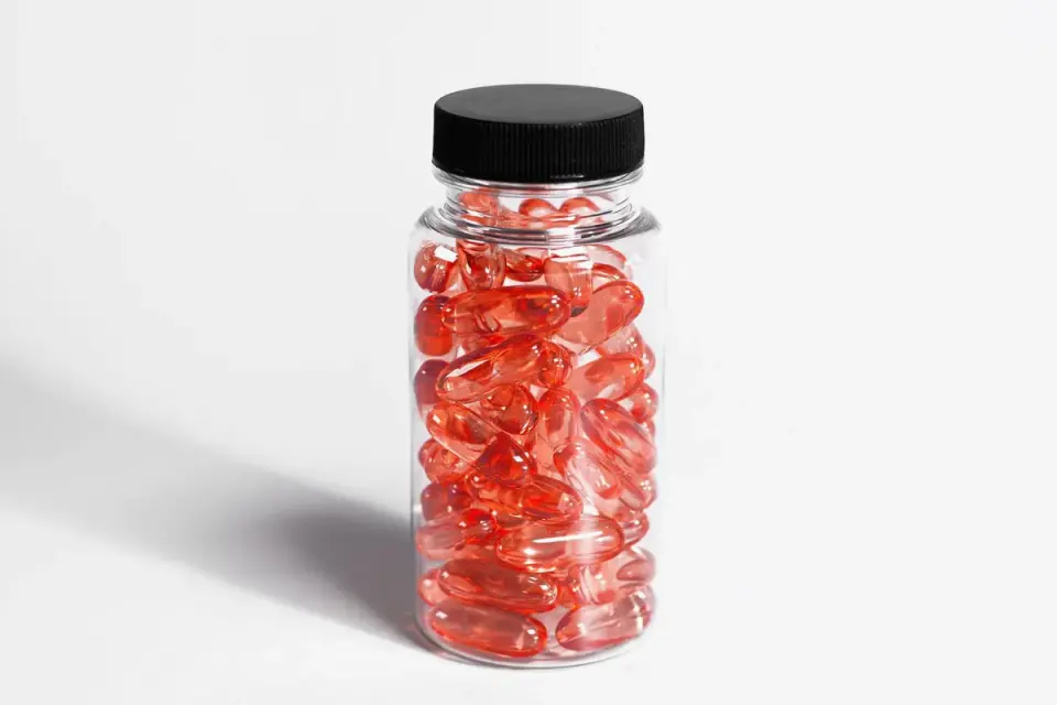 A bottle of flaxseed oil next to a jar of fish oil softgels on a counter