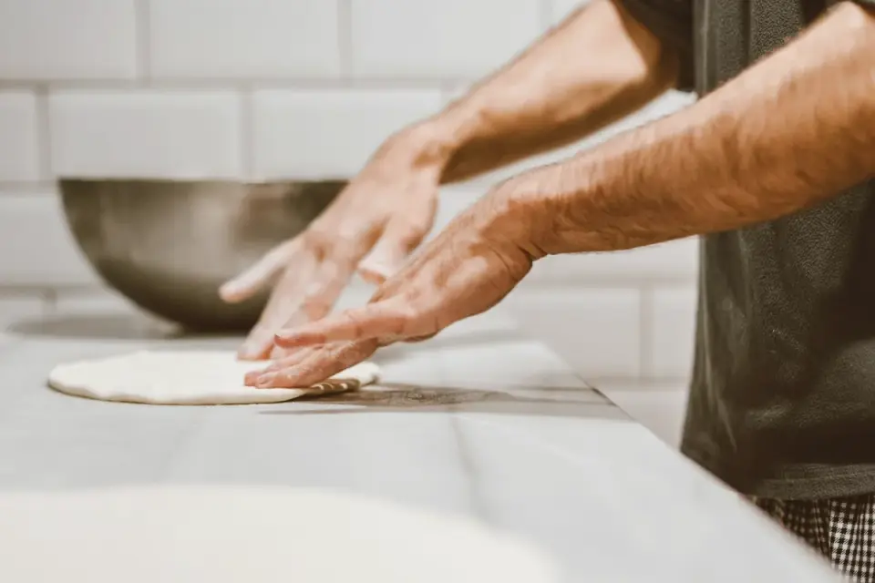 A bowl of raw bread dough rising on a kitchen counter