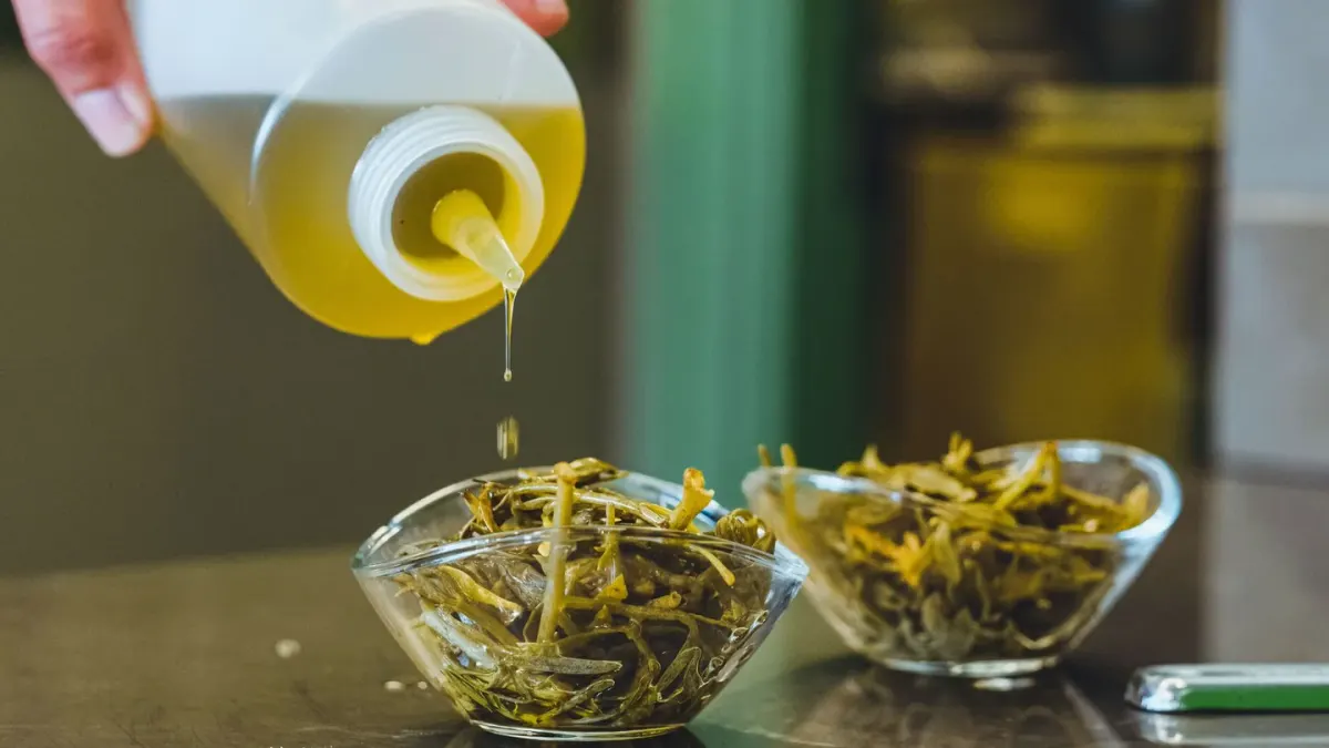 A dog owner adding liquid oil supplement to a bowl of kibble