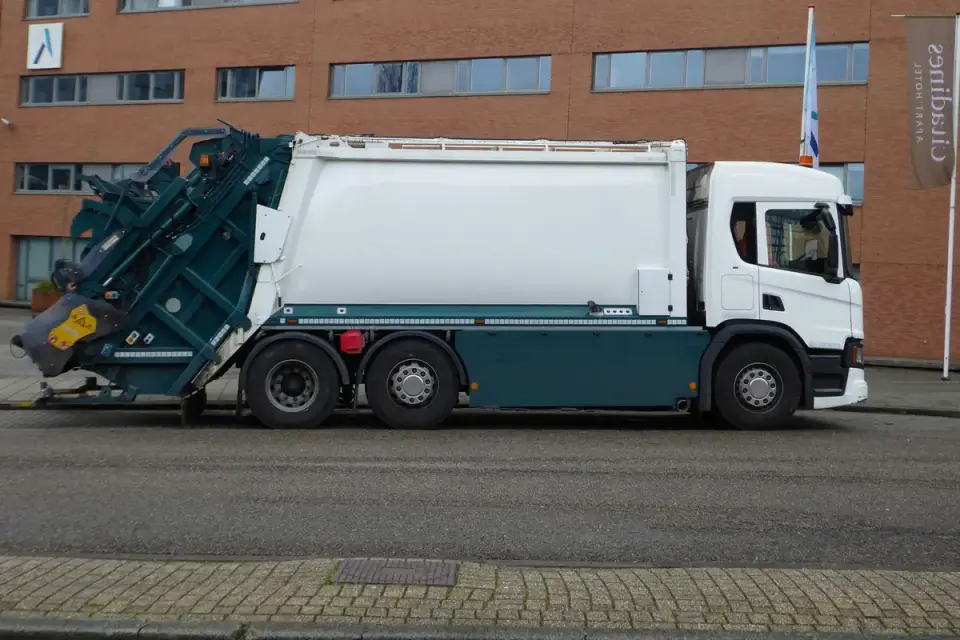 A garbage truck lifts a bin on a quiet residential street