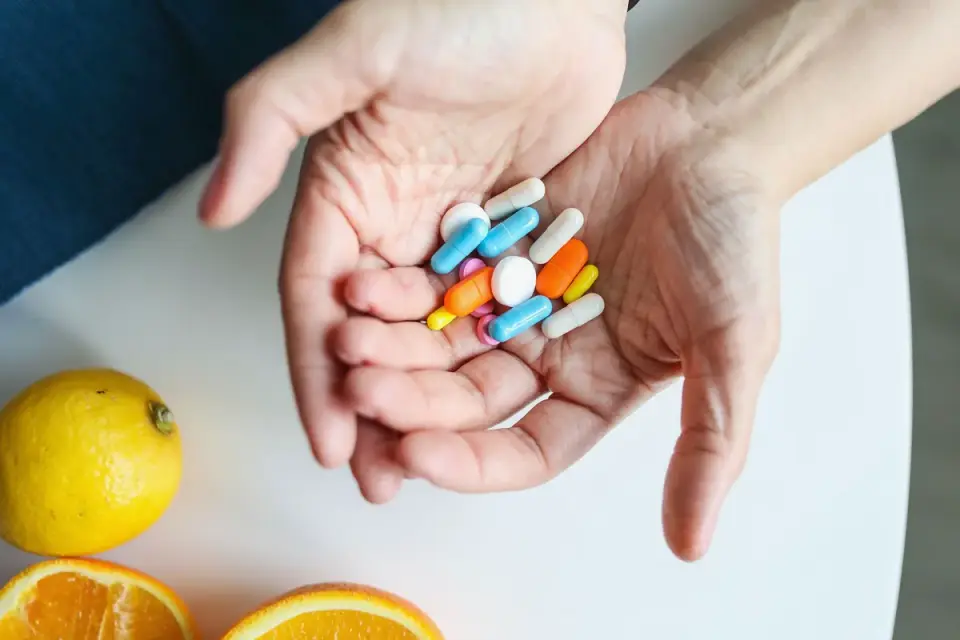 A hand holding two different dog supplement chews above a food bowl
