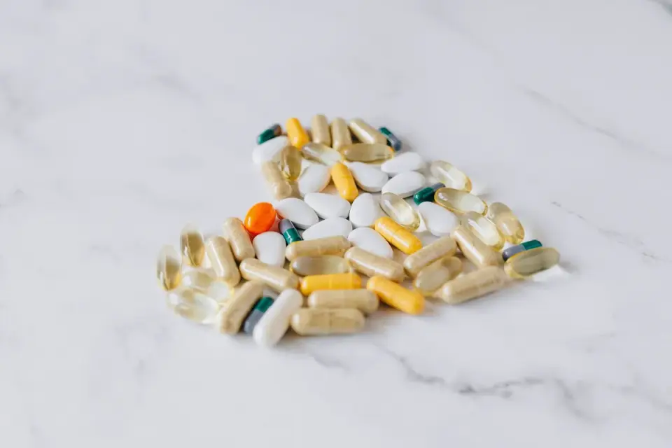 A pile of soft dog supplement chews next to a bottle of capsules on a kitchen counter