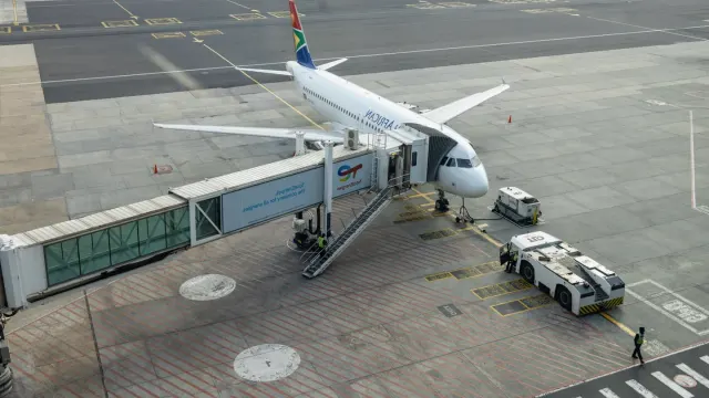 A small dog sitting calmly inside a soft-sided airline carrier at an airport gate