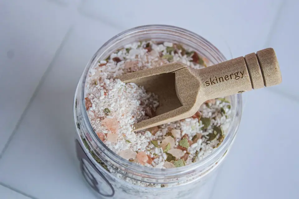 A small jar of dehydrated pumpkin powder with a wooden scoop resting beside it