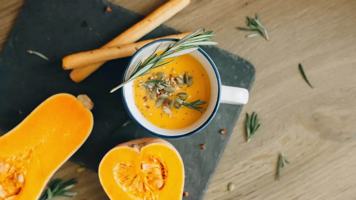 A spoonful of pumpkin puree next to a bowl of dry dog food on a kitchen counter