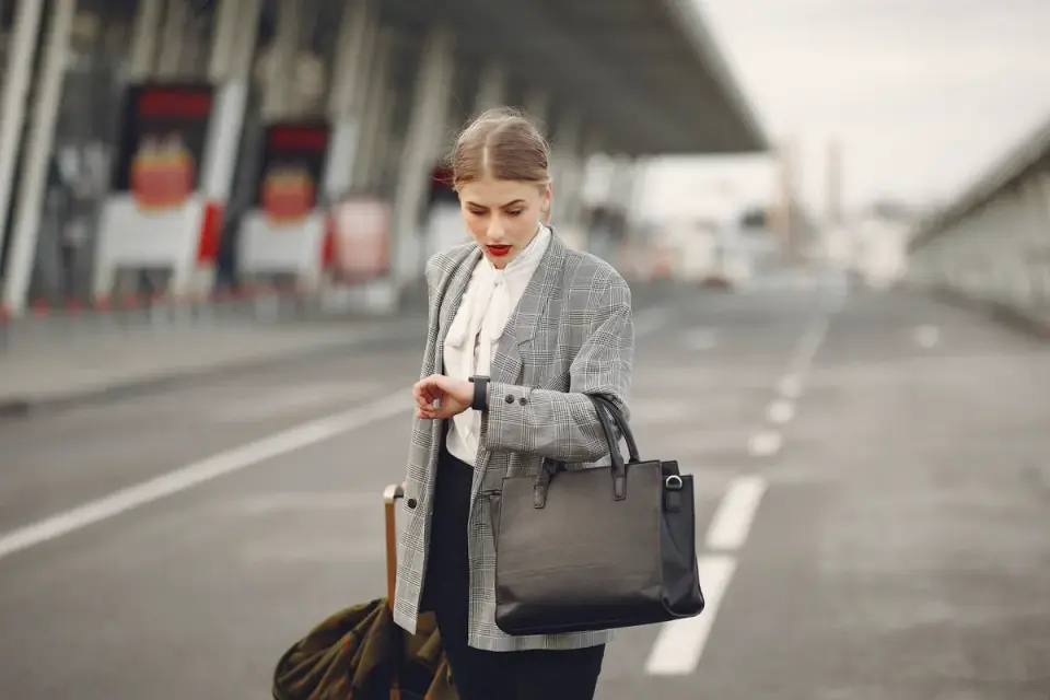A woman measures a soft-sided pet carrier against an airline sizing chart