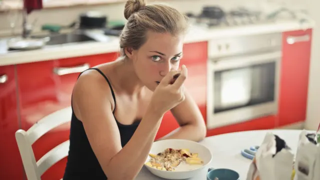 An adult dog eating kibble from a stainless steel bowl in a kitchen