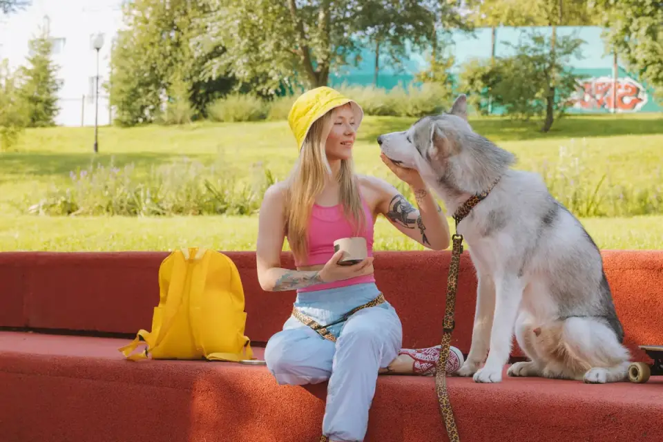 An owner rewarding a leashed dog with a treat during an outdoor training session