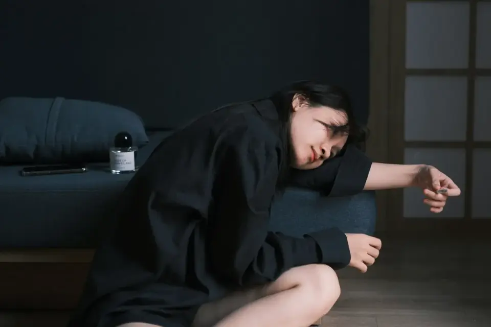 An owner sitting on the floor beside a puppy&#x27;s crate during a nighttime settling routine