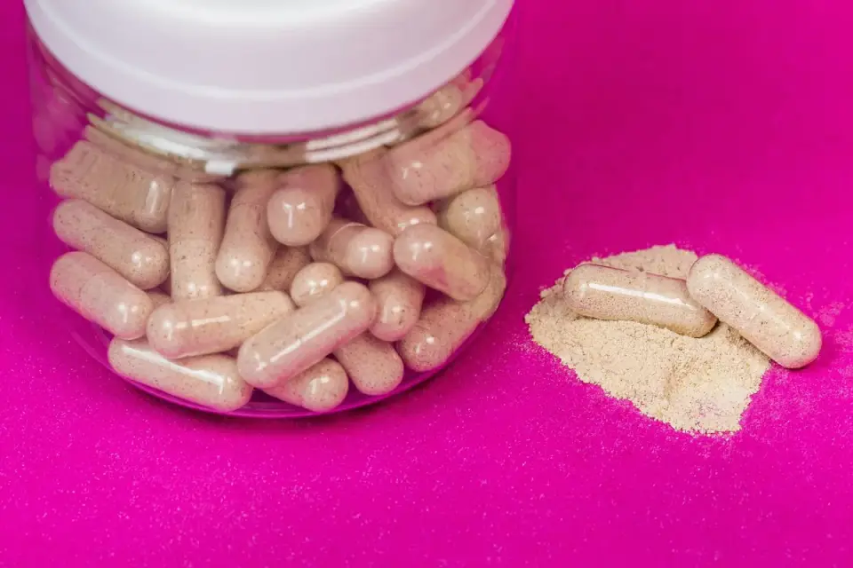 Ashwagandha root powder and capsules arranged on a wood table