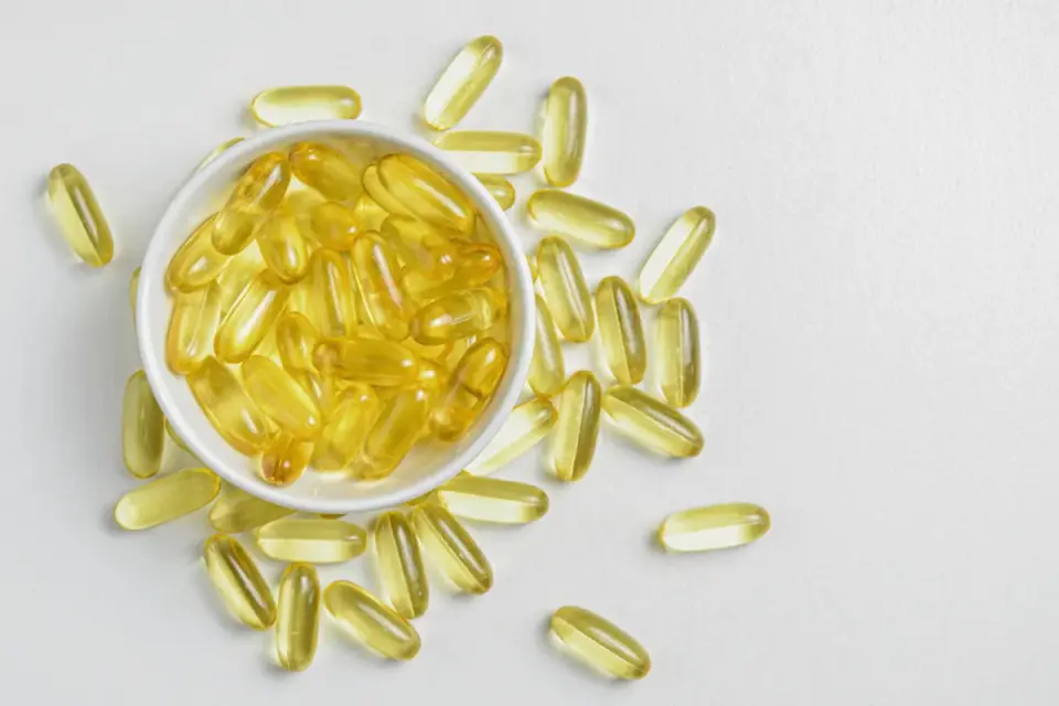 Bowl of dog kibble next to loose supplement capsules