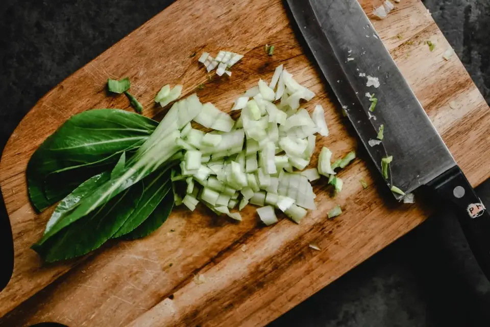 Chopped fresh green beans on a wooden cutting board with a dog watching nearby