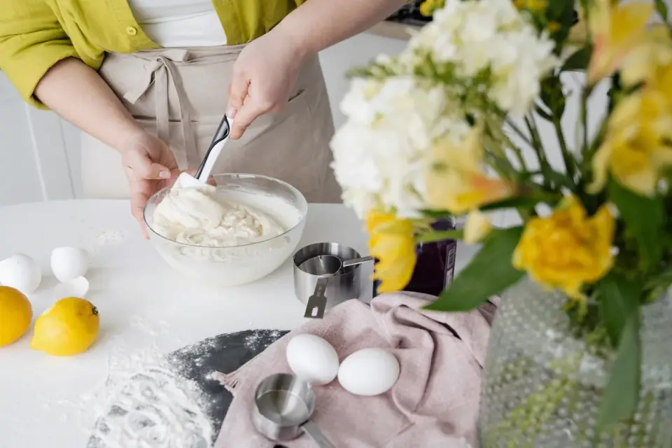 Dog owner stirring supplement powder into a bowl of food in a home kitchen
