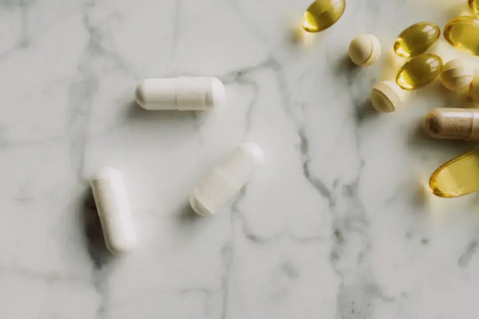 Fish oil softgel capsules placed beside a bowl of dry dog food
