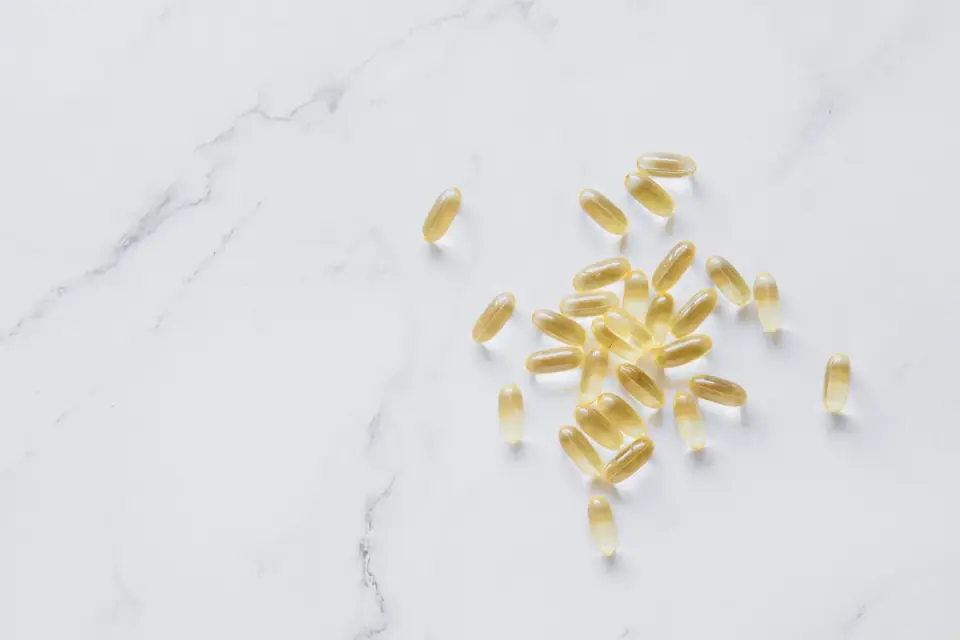 Fish oil softgel supplements next to a dog's food bowl