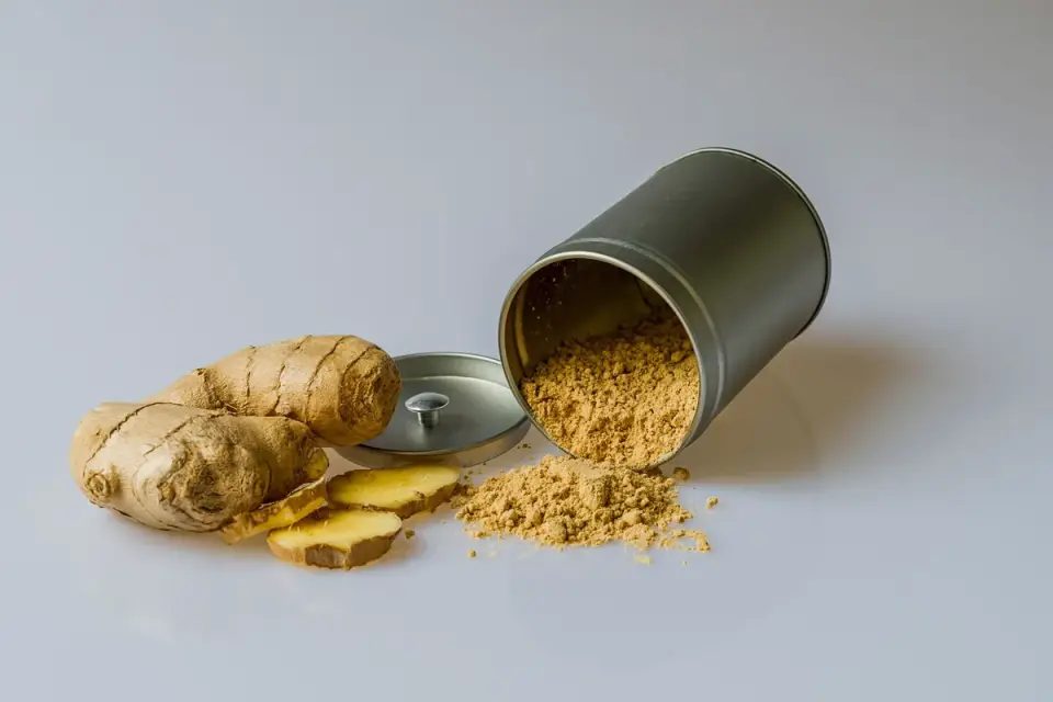 Fresh ginger root next to a small bowl of dog treats on a wooden countertop