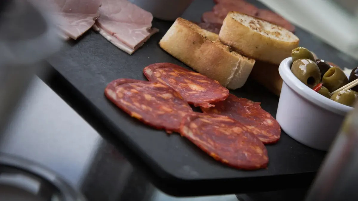 Slices of ham on a wooden cutting board with a dog looking on