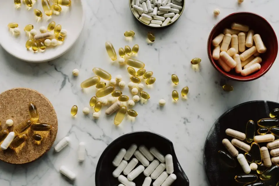 Soft-gel supplement capsules next to a dog's food bowl on a kitchen counter